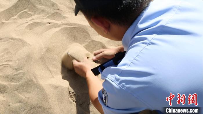 9月中旬、砂漠からスマホを掘り出す補助警官（撮影・高瑩）。