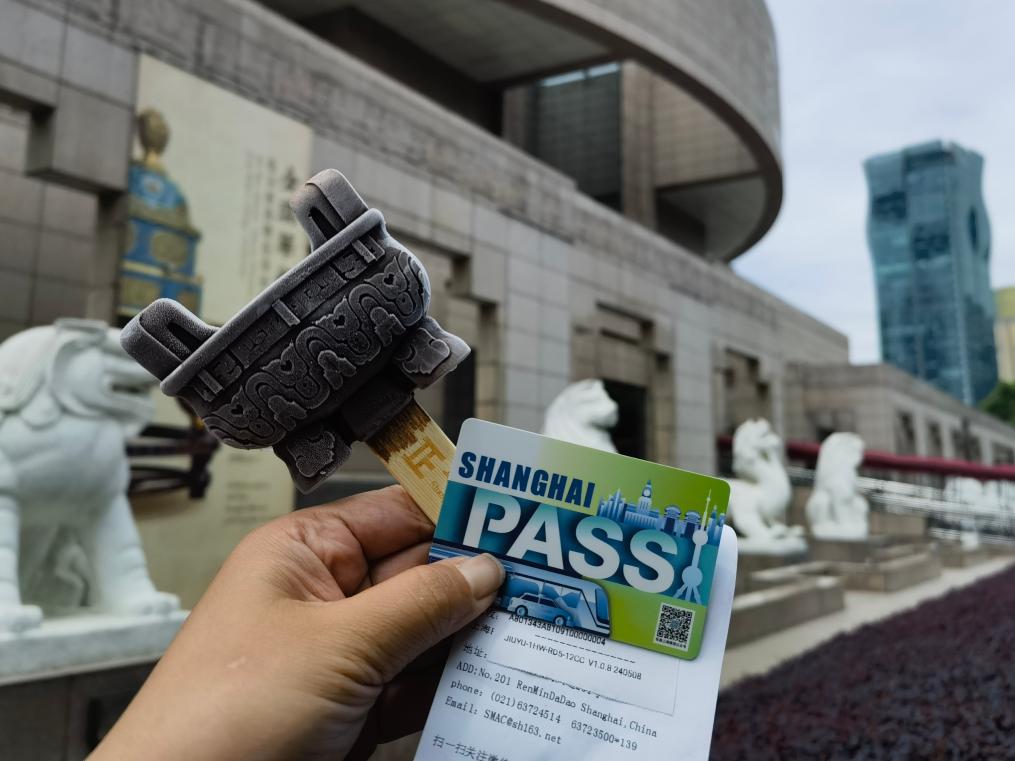 「Shanghai Pass」と上海博物館の文化クリエイティブアイスを手に写真を撮影する観光客（5月22日撮影・陳愛平）。