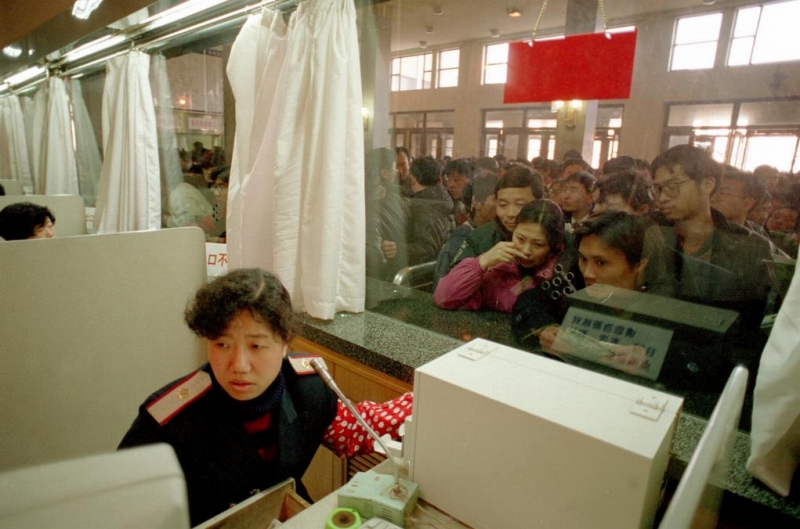 1997年1月18日、北京駅の切符窓口で乗客のためにコンピュータで切符を確認している販売係。（撮影・陳建力）