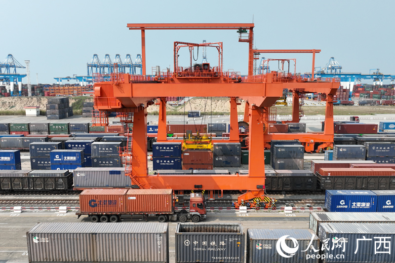 広西壮（チワン）族自治区欽州市の鉄道コンテナセンター駅で、自動化ガントリークレーンが自動車輸送コンテナ貨物を吊り上げている様子。（撮影・王勇）