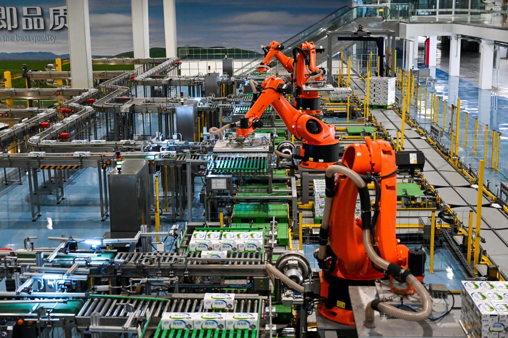 これは2025年7月28日に撮影されたフフホト市伊利現代スマート健康バレー液体ミルク世界製造モデル拠点で、ロボットアームが牛乳製品を箱詰めしている様子。撮影・李志鵬