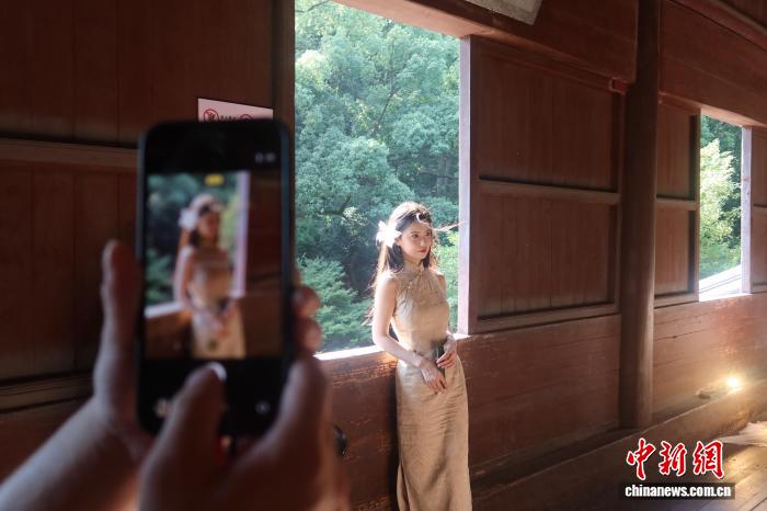 六和塔の木製の窓をバックに写真を撮影する女性(8月30日撮影・孫琳茹)。