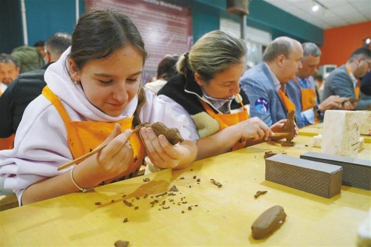ベラルーシからの観光客のナドゼヤさん(写真一番左側)と母親のアンジェラさん(写真左から2人目)が兵馬俑のレプリカを作っている様子(資料写真/撮影・王三合)。