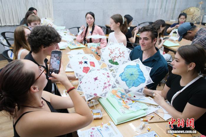 2025年6月、浙江省杭州市の中国刀剪剣博物館で、自分でデザインした傘布を手に写真を撮影する外国人たち（撮影・曹丹）。