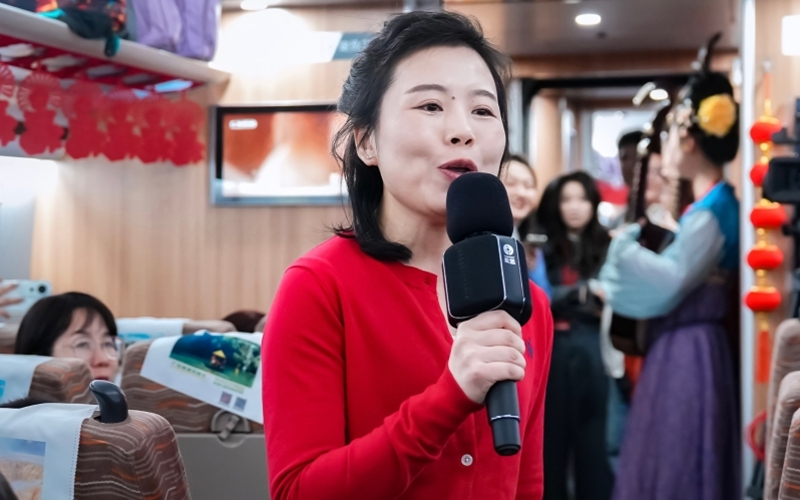 2月10日、無料の特別列車の車内でマイクを持って話す女性（撮影・王西妍）。