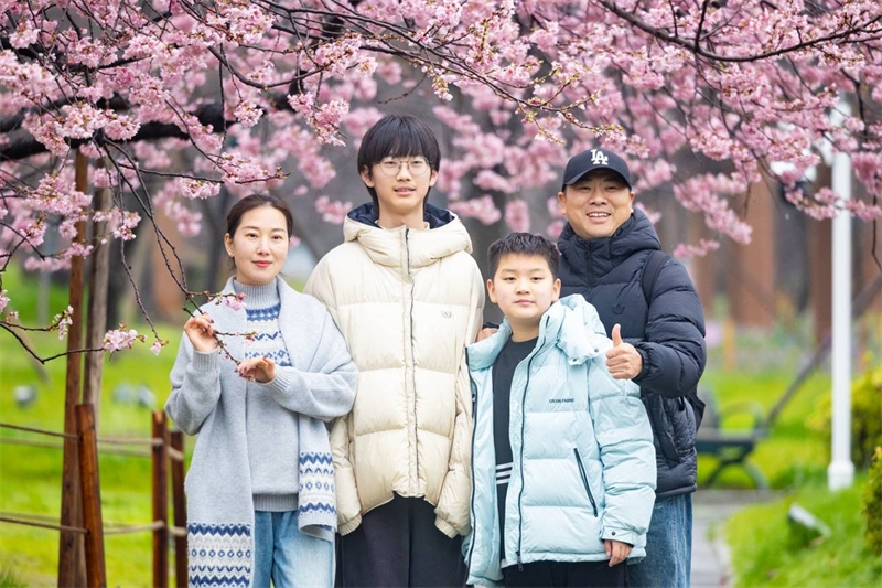 武漢東湖桜花園で桜をバックに記念撮影をする家族連れ（3月1日撮影・何宇欣）。