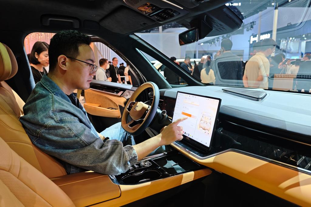 2026北京モーターショーの極氪（ZEEKR）の展示エリアで、新エネ車のスマート機能を体験する男性（撮影・唐詩凝）。