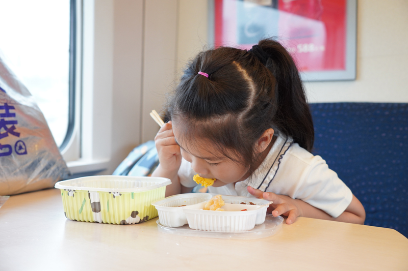 高速列車でお子様弁当を食べる女の子（資料写真、撮影・王聖凱）。