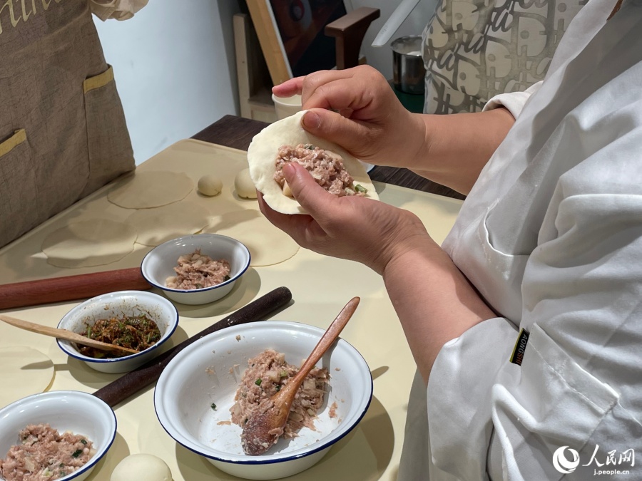 左手の親指で餡を押さえながら、右手で包んでいく（撮影・勝又あや子）
