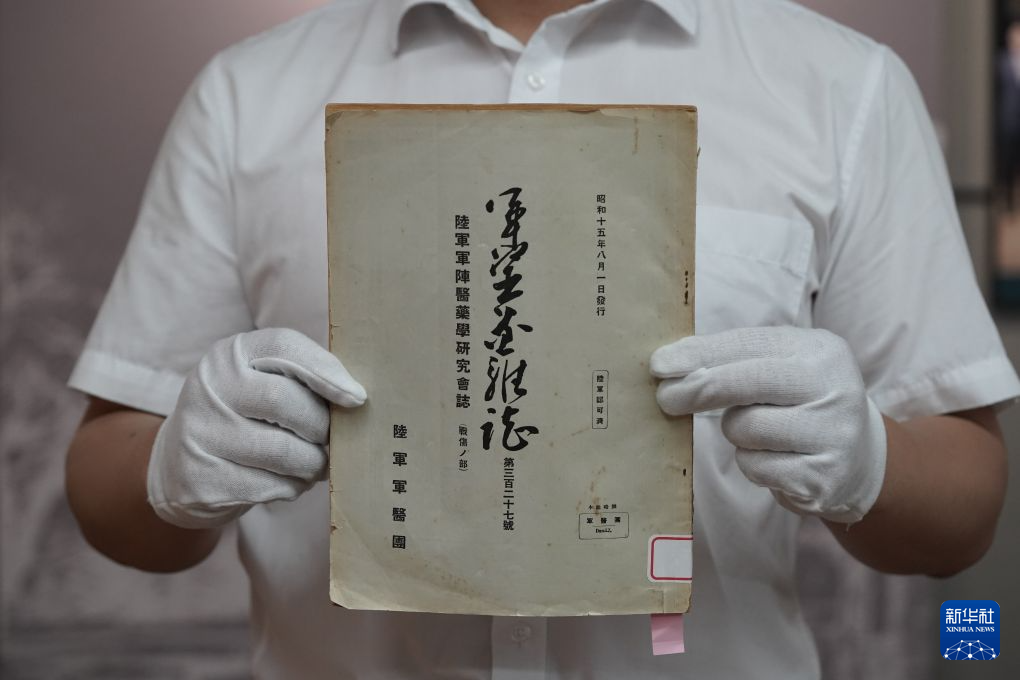 1940年8月1日発行の『軍医団雑誌』原本を示す侵華日軍第七三一部隊罪証陳列館の研究員（6月23日撮影・何山）
