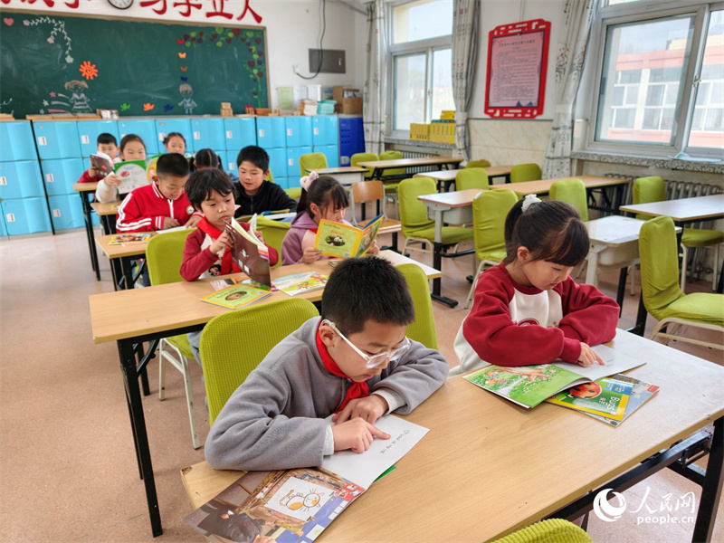 英語の絵本を読む東邵渠鎮中心小学校の2年生の児童たち（撮影・常沙）。