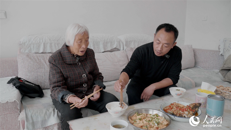 一人暮らしの刁淑芳さんに昼食を作り、一緒に食べる李全生さん（撮影・彭昱凱）。