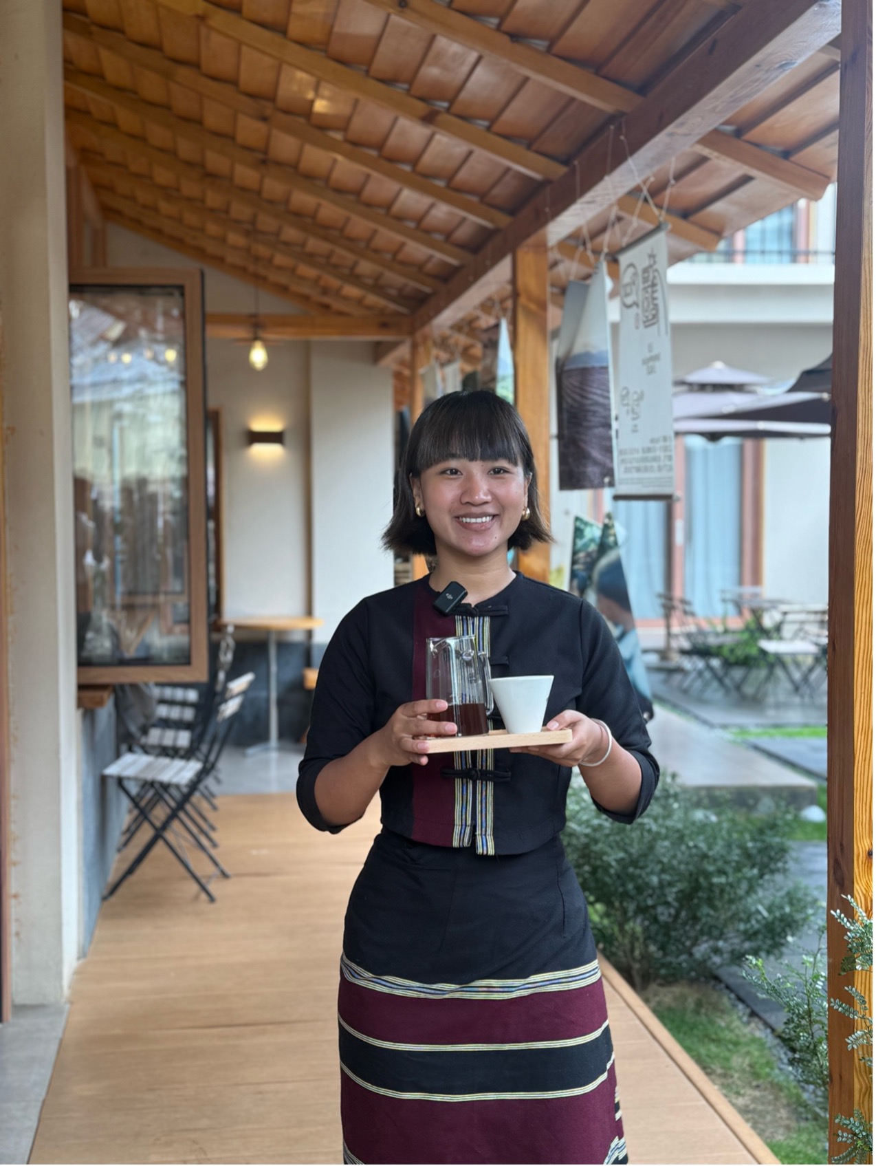 自身が経営するカフェでコーヒーを運ぶ趙華さん(撮影・虎遵会)。