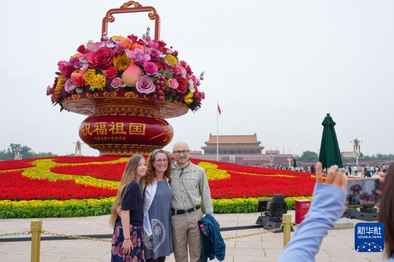 天安門広場で、「祝福祖国」巨大花かごをバックに記念写真を撮影する3人の米国人観光客（9月25日撮影・鞠煥宗）。