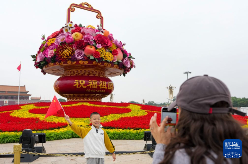 天安門広場で、「祝福祖国」巨大花かごをバックに写真を撮影する観光客（9月25日撮影・鞠煥宗）。