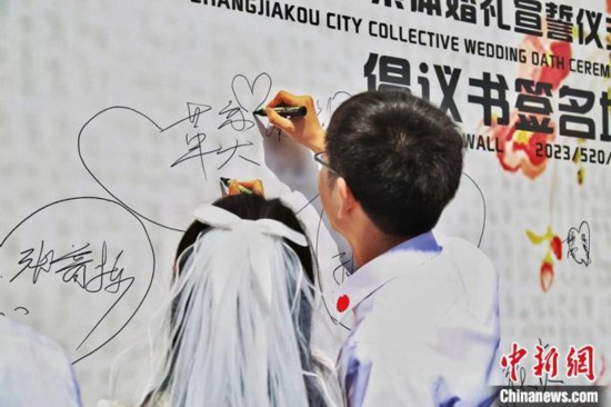 5月20日、河北省張家口市で開催された第1回結婚の誓い合同セレモニーで、自分の名前を書く新郎新婦（撮影・王慧）。