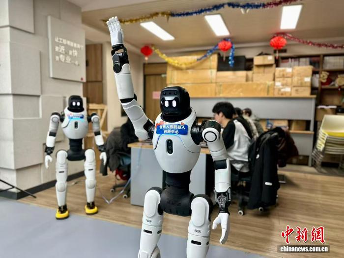 甘粛省蘭州市城関区において、人型ロボットに指定のアクションをさせるロボット訓練士ら(3月13日撮影・閆姣)。