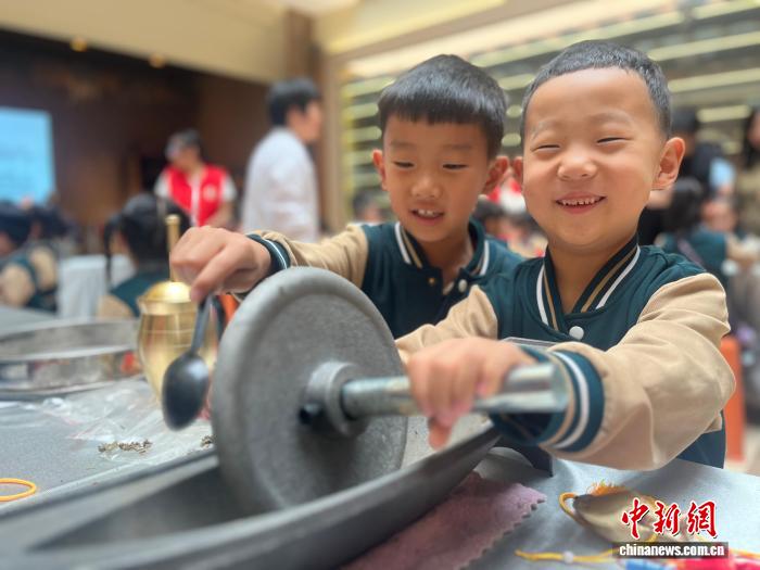 薬研を使って生薬を粉末にする小学生たち（撮影・範麗芳）。