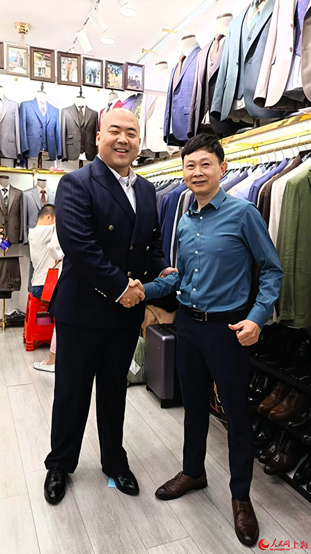 店主と記念写真を撮影する王俊生さん（写真左、写真提供・取材対象者）。