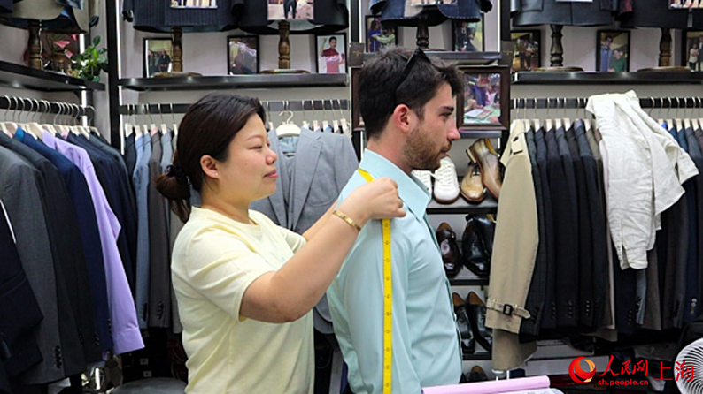外国人男性の肩幅を測る店主の陳琴さん（撮影・楊雯）。